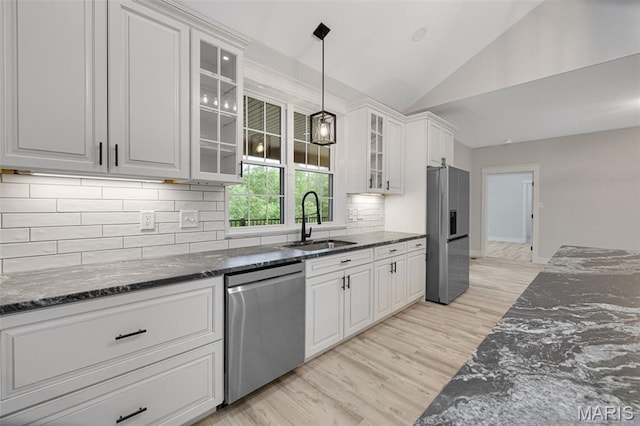 10102 Springer Dr, Bonne Terre, MO 63628 - kitchen featuring appliances with stainless steel finishes, a sink, vaulted ceiling, dark stone counters, and light wood-style floors