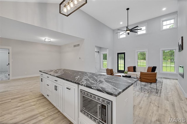 10102 Springer Dr, Bonne Terre, MO 63628 - kitchen featuring stainless steel microwave, a ceiling fan, light wood finished floors, a high ceiling, and open floor plan