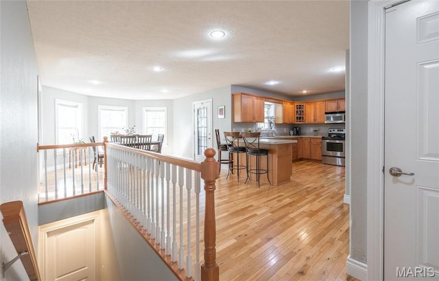 21438 Lancaster Ln, Waynesville, MO 65583 - kitchen featuring appliances with stainless steel finishes, light wood-style flooring, a breakfast bar area, glass insert cabinets, and a peninsula