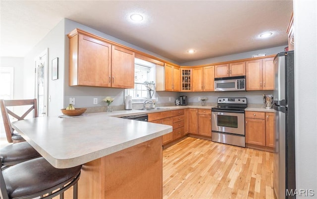 21438 Lancaster Ln, Waynesville, MO 65583 - kitchen with appliances with stainless steel finishes, a peninsula, light countertops, light wood finished floors, and a breakfast bar