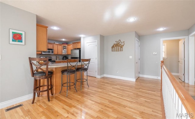 21438 Lancaster Ln, Waynesville, MO 65583 - kitchen with appliances with stainless steel finishes, recessed lighting, a peninsula, a kitchen bar, and light wood-style flooring