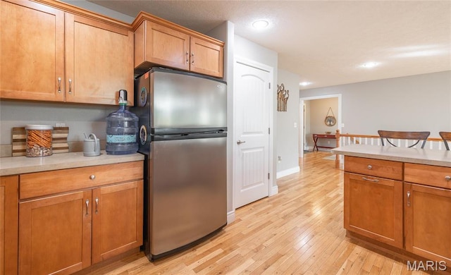 21438 Lancaster Ln, Waynesville, MO 65583 - kitchen with freestanding refrigerator, light wood-style flooring, light countertops, recessed lighting, and brown cabinetry