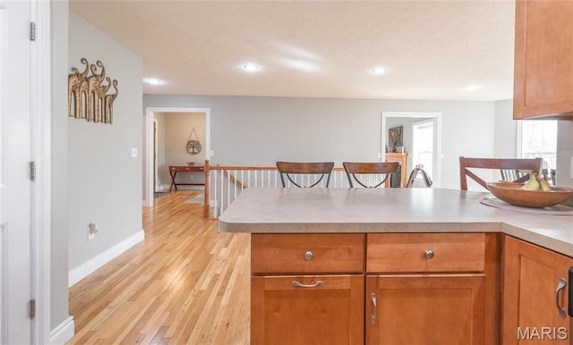 21438 Lancaster Ln, Waynesville, MO 65583 - kitchen featuring a peninsula, light wood-style flooring, brown cabinetry, light countertops, and recessed lighting
