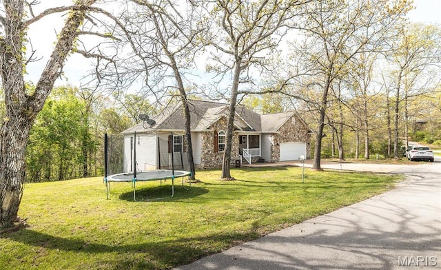 21438 Lancaster Ln, Waynesville, MO 65583 - view of front facade featuring a trampoline, concrete driveway, a front yard, and a garage