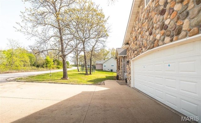 21438 Lancaster Ln, Waynesville, MO 65583 - view of side of home with stone siding, a garage, a lawn, and driveway