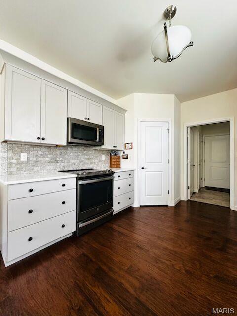 kitchen with stainless steel appliances, light countertops, tasteful backsplash, and dark wood-type flooring