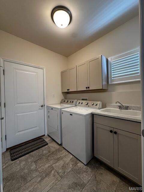 washroom featuring cabinet space, washing machine and dryer, and stone finish floors