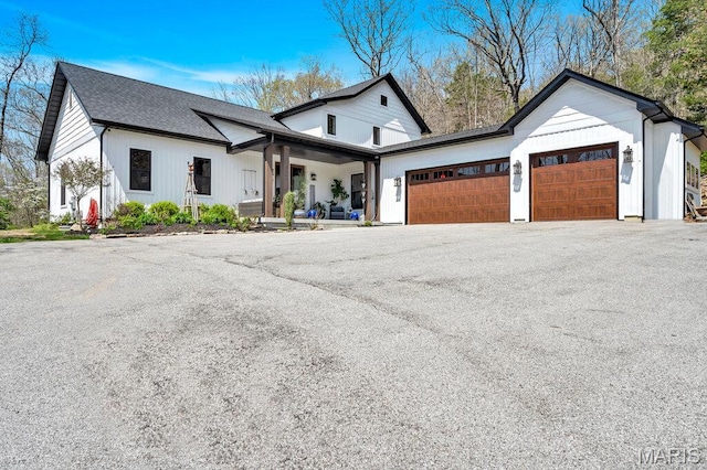 2509 Prairie Hollow Rd, Imperial, MO 63052 - modern farmhouse with a garage, covered porch, driveway, and a shingled roof