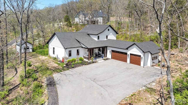2509 Prairie Hollow Rd, Imperial, MO 63052 - modern inspired farmhouse featuring a garage, asphalt driveway, roof with shingles, a view of trees, and an outbuilding