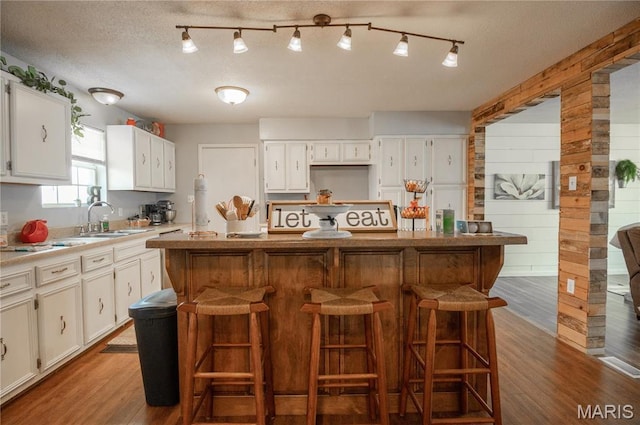 121 Ripley 142e-18, Doniphan, MO 63935 - kitchen with a sink, wood finished floors, a kitchen bar, white cabinets, and wooden walls