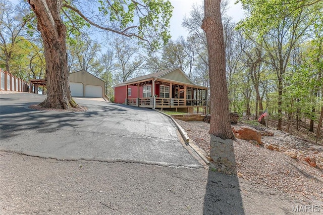 chalet / cabin featuring a garage, an outdoor structure, and a porch
