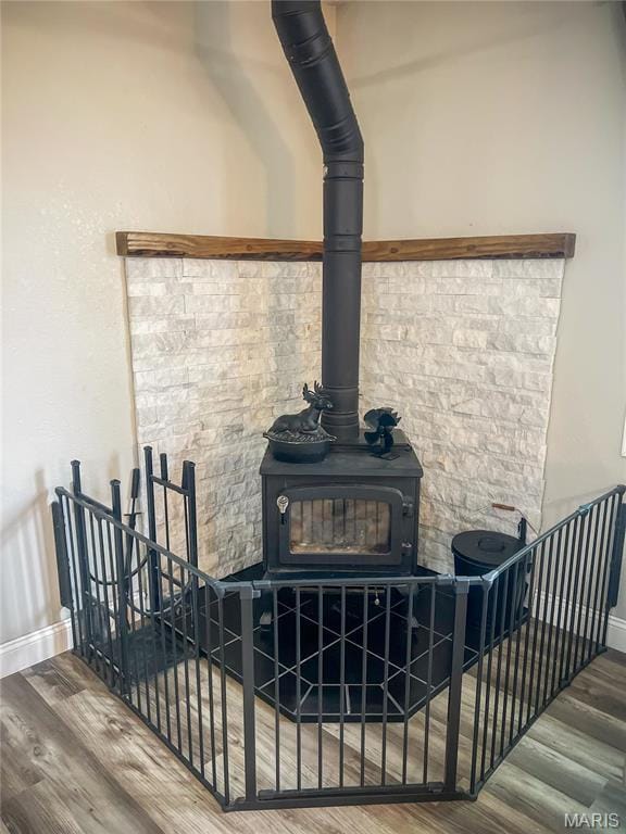 detailed view of a wood stove, wood finished floors, and baseboards