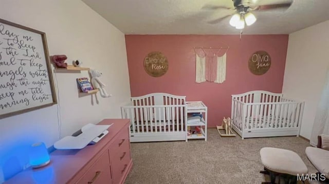bedroom with carpet floors, a nursery area, and a ceiling fan