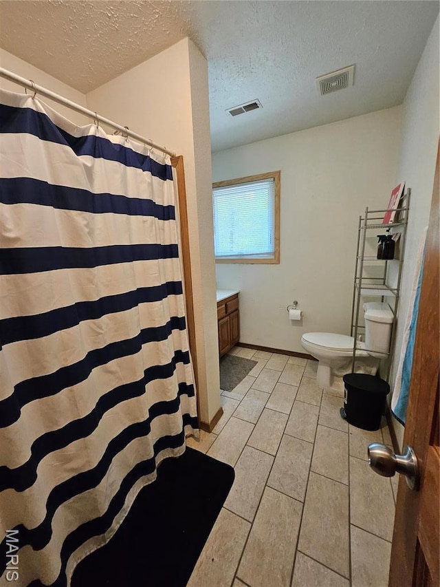 full bathroom featuring a textured ceiling, toilet, a shower with curtain, tile patterned floors, and vanity