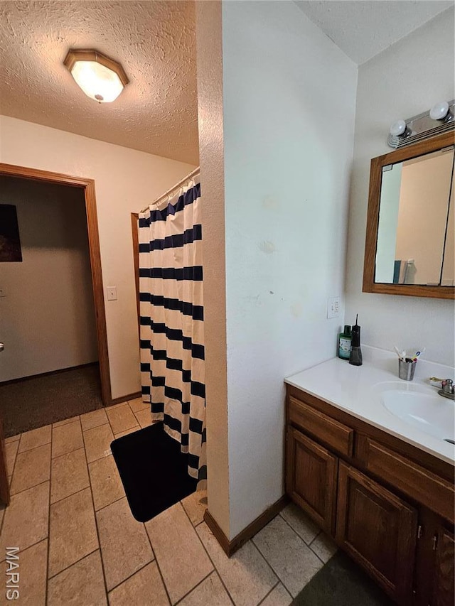 full bath featuring vanity, tile patterned flooring, a textured ceiling, a shower with curtain, and baseboards