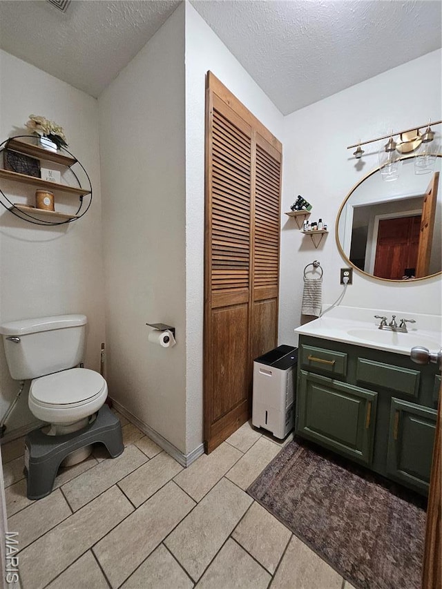 bathroom with toilet, a textured ceiling, and vanity
