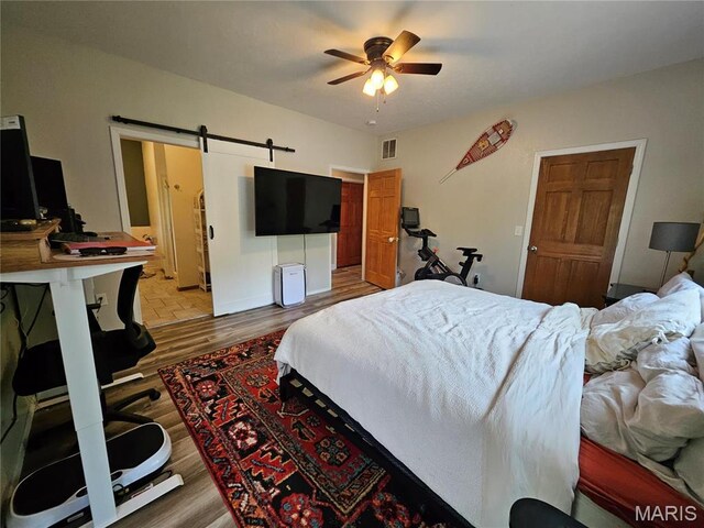 bedroom featuring a barn door and wood finished floors