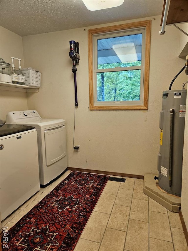 laundry area featuring water heater, washing machine and clothes dryer, baseboards, a textured ceiling, and light tile patterned floors