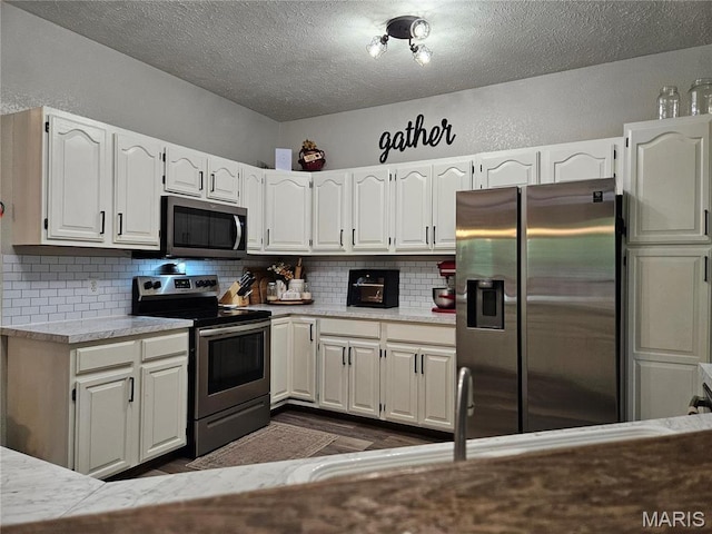 kitchen with stainless steel appliances, white cabinets, a textured ceiling, tasteful backsplash, and a textured wall