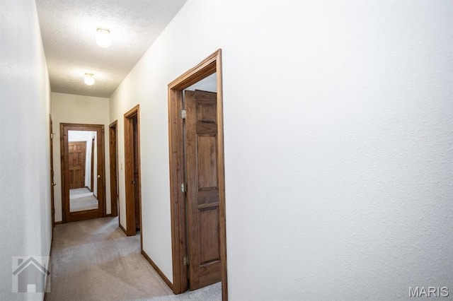 220 April Dr, Saint Robert, MO 65584 - hallway featuring light colored carpet, baseboards, and a textured ceiling