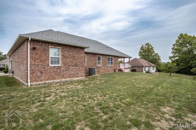 220 April Dr, Saint Robert, MO 65584 - back of house featuring brick siding, a lawn, a shingled roof, and central AC