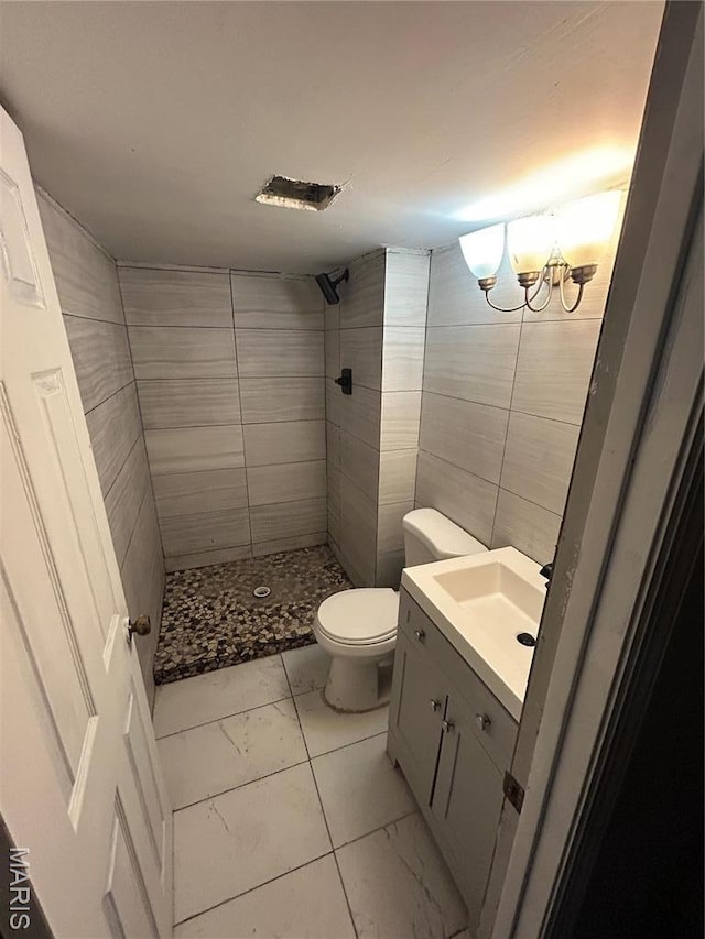 352 Sturbridge Village Dr, Hazelwood, MO 63042 - bathroom featuring marble look tiles, tiled shower, toilet, vanity, and tile walls