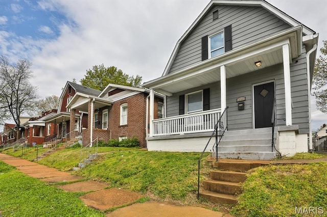 4417 Wallace St, Saint Louis, MO 63116 - view of front facade featuring a porch, a gambrel roof, a front lawn, and brick siding