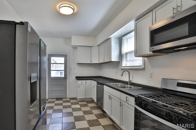4417 Wallace St, Saint Louis, MO 63116 - kitchen with appliances with stainless steel finishes, a sink, dark countertops, white cabinets, and dark floors
