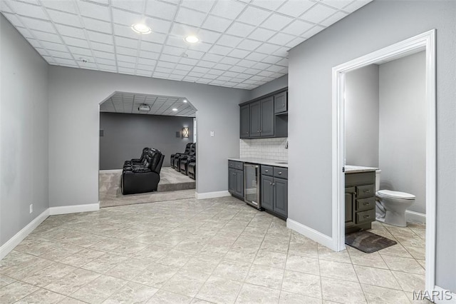 312 Oak Forest Dr, Jackson, MO 63755 - kitchen featuring light countertops, wine cooler, tasteful backsplash, gray cabinetry, and arched walkways