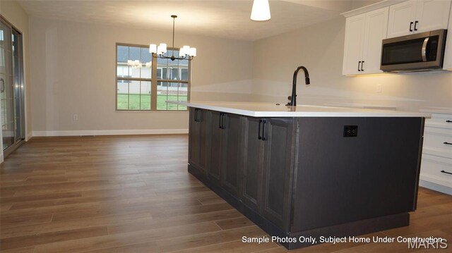 2028 Ravenel, Swansea, IL 62226 - kitchen with stainless steel microwave, white cabinetry, wood finished floors, and an island with sink