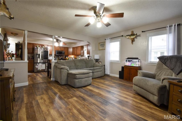 311 S Hibbard St, Staunton, IL 62088 - living area featuring a ceiling fan, dark wood finished floors, arched walkways, a textured ceiling, and baseboards