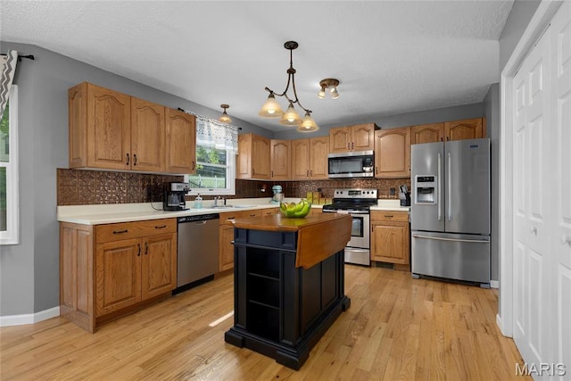 22 Whispering Oaks Dr, Washington, MO 63090 - kitchen with stainless steel appliances, light wood finished floors, tasteful backsplash, pendant lighting, and a kitchen island