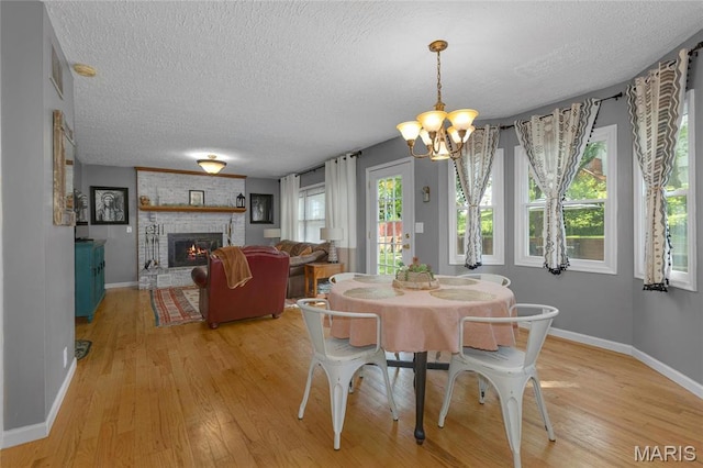 22 Whispering Oaks Dr, Washington, MO 63090 - dining area with a textured ceiling, a chandelier, light wood-type flooring, baseboards, and a fireplace