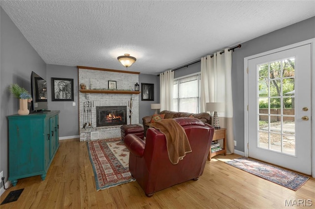22 Whispering Oaks Dr, Washington, MO 63090 - living area with a textured ceiling, light wood finished floors, plenty of natural light, a brick fireplace, and baseboards
