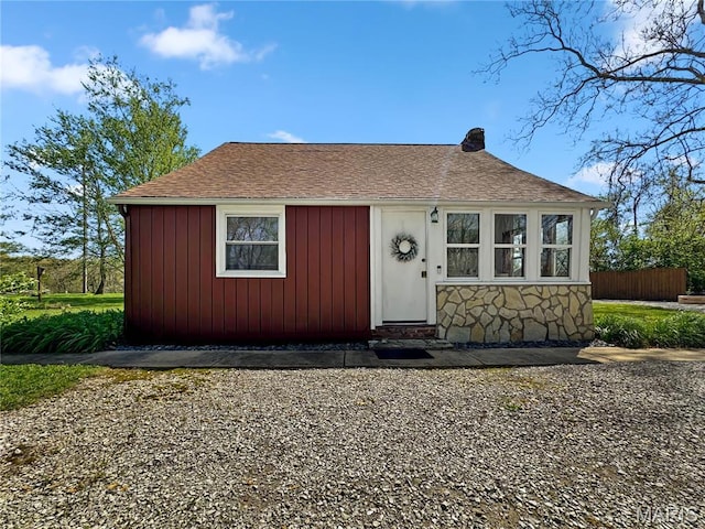 bungalow-style house with stone siding and roof with shingles