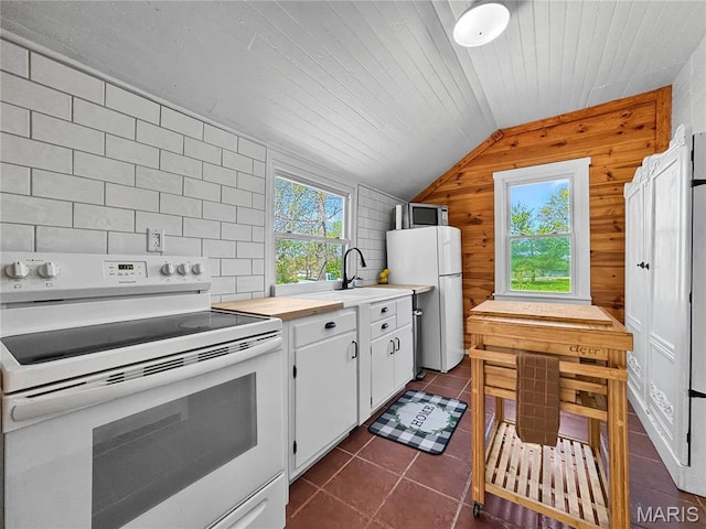 kitchen featuring white appliances, vaulted ceiling, plenty of natural light, light countertops, and white cabinets