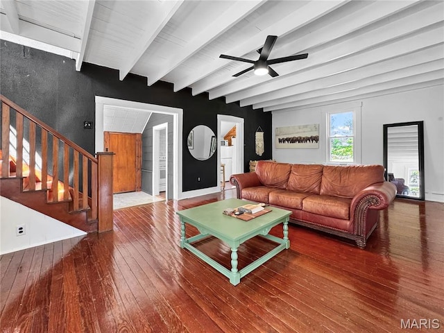 living area featuring hardwood / wood-style flooring, a ceiling fan, beamed ceiling, and stairs