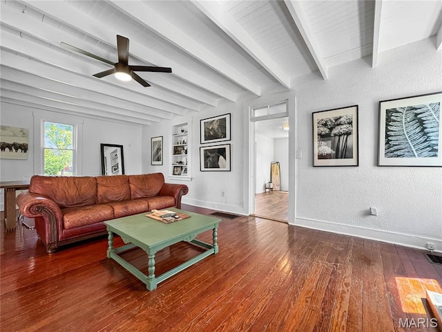 living area featuring a ceiling fan, hardwood / wood-style flooring, baseboards, beam ceiling, and a textured wall