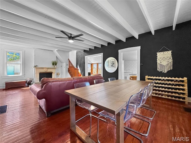 living room featuring wood finished floors, a fireplace, beamed ceiling, and ceiling fan