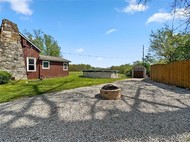 view of yard featuring an outdoor fire pit, a shed, a covered pool, and an outbuilding