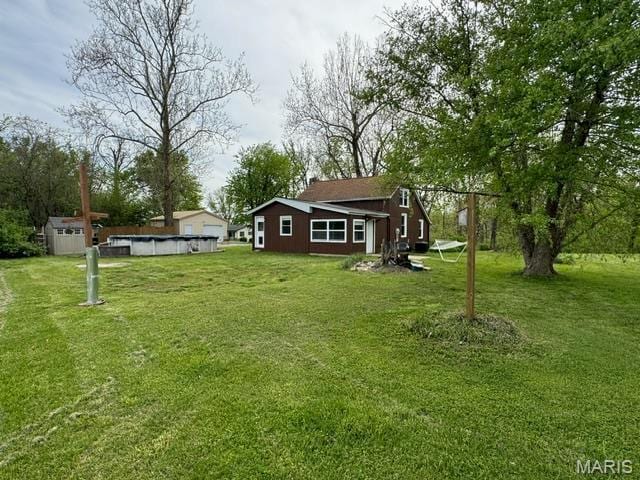 view of grassy yard with an outdoor pool, a storage unit, and an outdoor structure