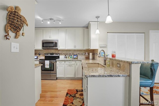 1709 Highview Circle Ct, Ballwin, MO 63021 - kitchen with appliances with stainless steel finishes, a sink, a peninsula, light stone counters, and light wood-style flooring