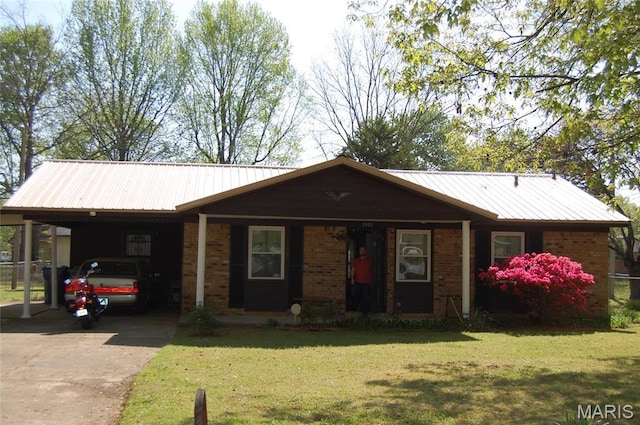 single story home featuring concrete driveway, a front lawn, brick siding, and metal roof