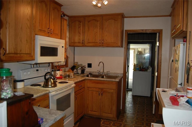 kitchen with white appliances, a sink, washer / clothes dryer, brown cabinets, and ornamental molding