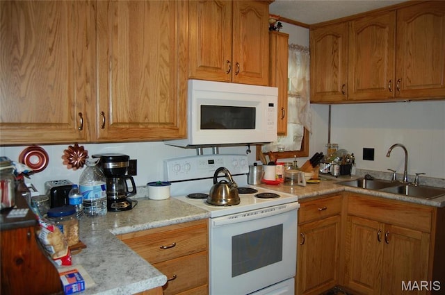 kitchen featuring white appliances, a sink, and brown cabinets
