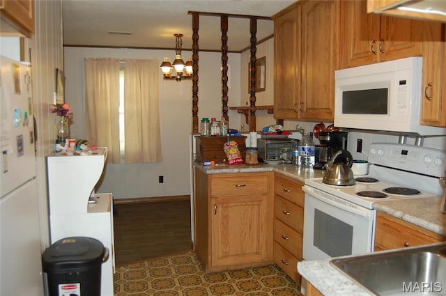 kitchen featuring white appliances, light countertops, pendant lighting, brown cabinetry, and baseboards