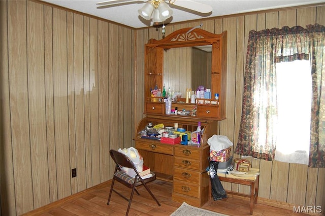 office featuring wood finished floors, ceiling fan, wood walls, baseboards, and ornamental molding