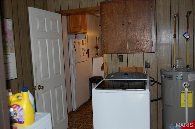 laundry room featuring water heater, cabinet space, wooden walls, and washer and dryer