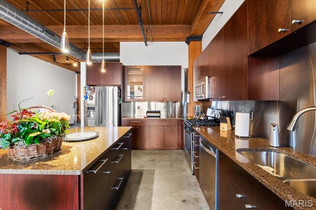 kitchen with appliances with stainless steel finishes, a sink, modern cabinets, hanging light fixtures, and concrete flooring