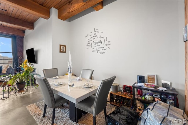 dining space with finished concrete floors, wooden ceiling, and beam ceiling